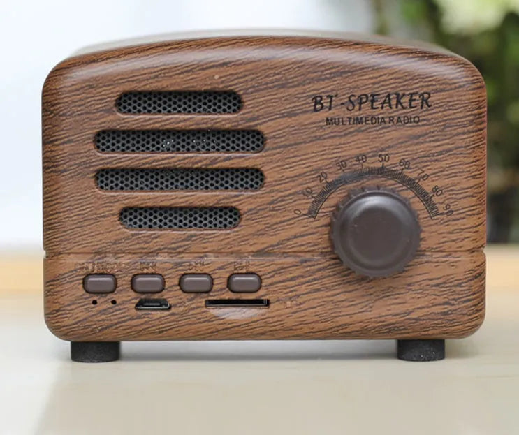 Vintage-style wood grain finish Bluetooth speaker on a table, showing compact size and USB port.