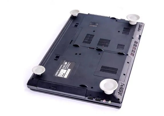 Four grey plastic laptop cooling pads, two large and two small, placed under a silver laptop on a wooden desk.