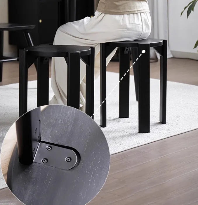 Stackable round iron dining stool in smoked black, walnut, cherrywood, or cream colour on a tiled floor.