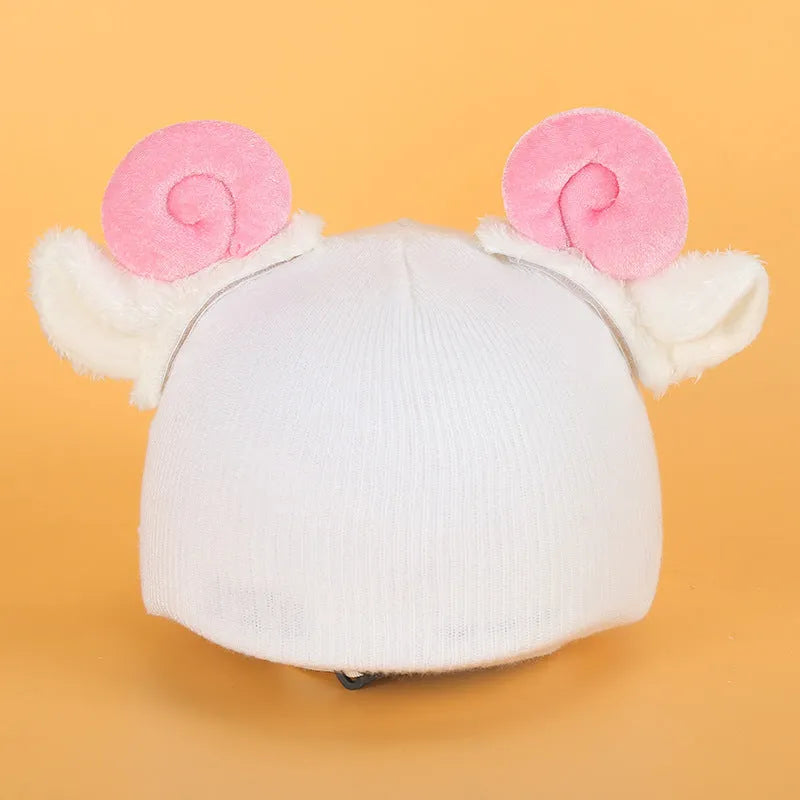 A plush fabric cartoon-themed decoration attached to the top of a blue ski helmet on a snowy slope.