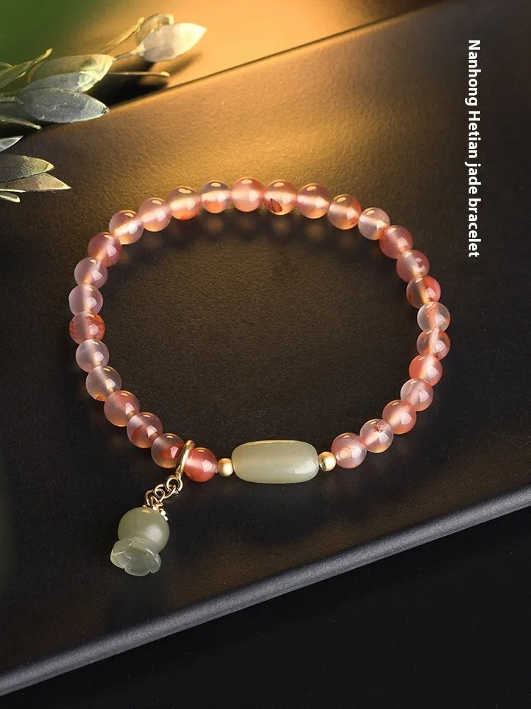 Polished Nanhong agate bracelet with ethnic bamboo-joint and flower design on a wrist.