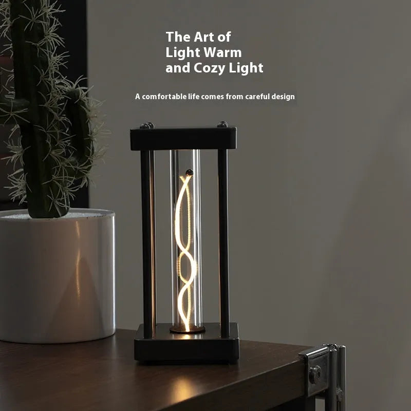 Metallic gray acrylic square night lamp with curved wire on a desk