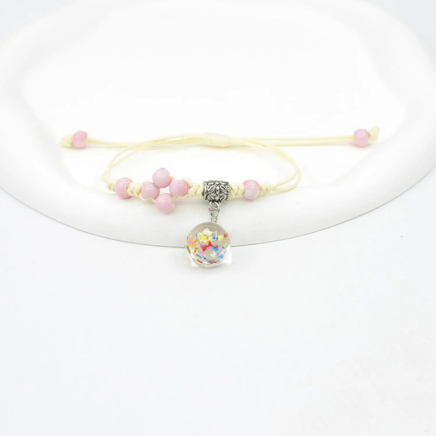 Close-up of a hand-woven glass bracelet with large 1.4cm beads containing real dried flowers and lace floral detailing.