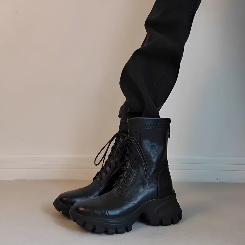 Black thick-soled motorcycle boots with back zipper, lace-up front, round toe, and rubber sole on a neutral background