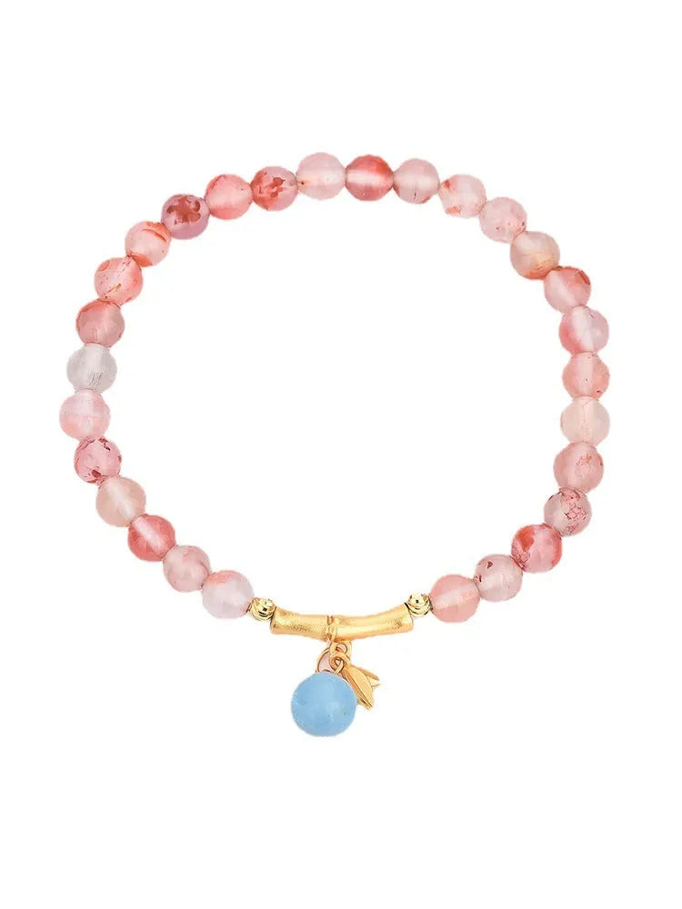 Polished Nanhong agate bracelet with ethnic bamboo-joint and flower design on a wrist.