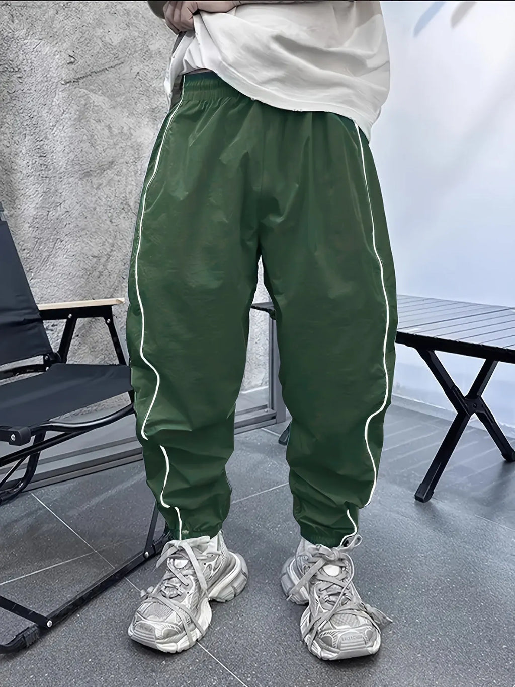Man wearing loose-fit cropped sports trousers in bamboo fibre, showing army green colour and elastic waist.