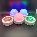 Compact colourful gradient 3D shooting night light with remote control on a desk.