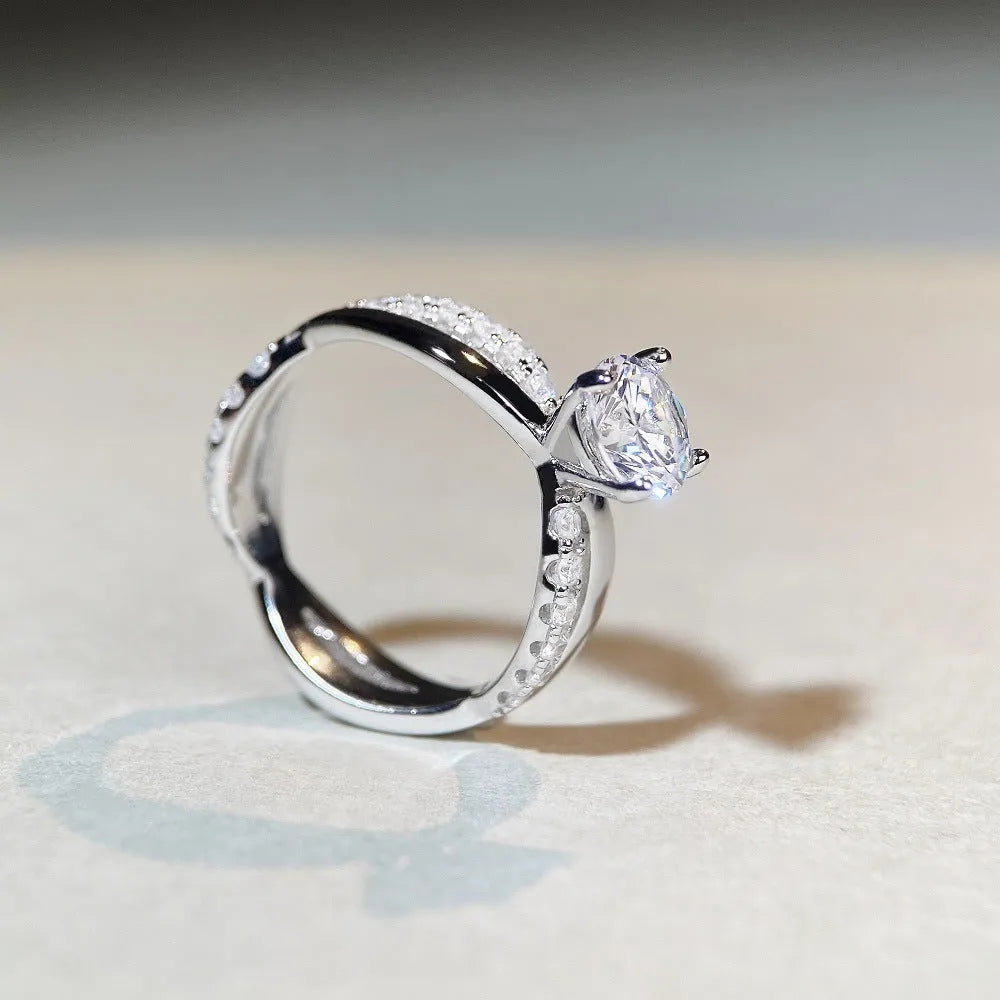 Geometric twisted silver band ring with a 1 carat round moissanite stone in a four-claw setting.