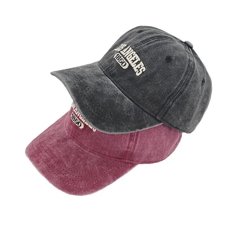 Retro beige peaked cap with embroidered letters, showing distressed fabric texture and adjustable strap.