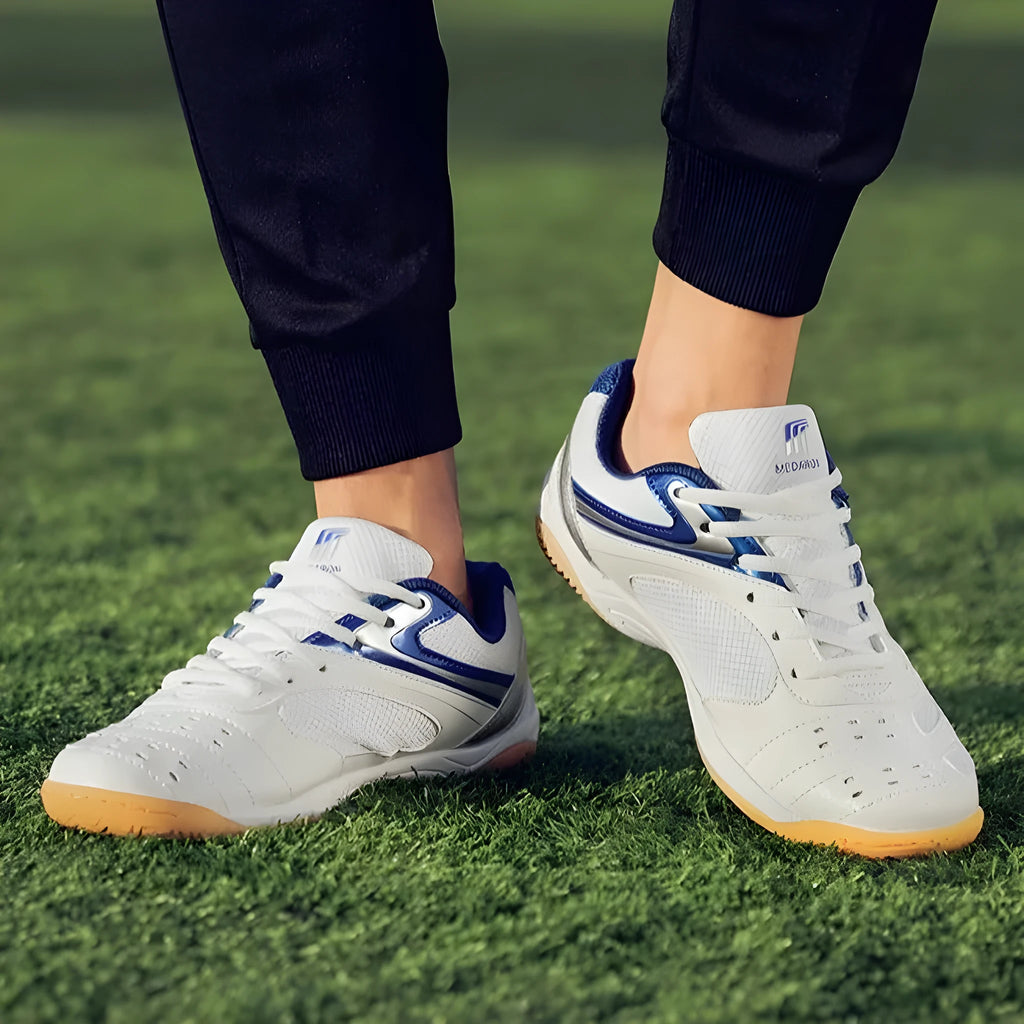 Table tennis training sneaker in white and blue with synthetic leather and mesh upper and lace-up front.