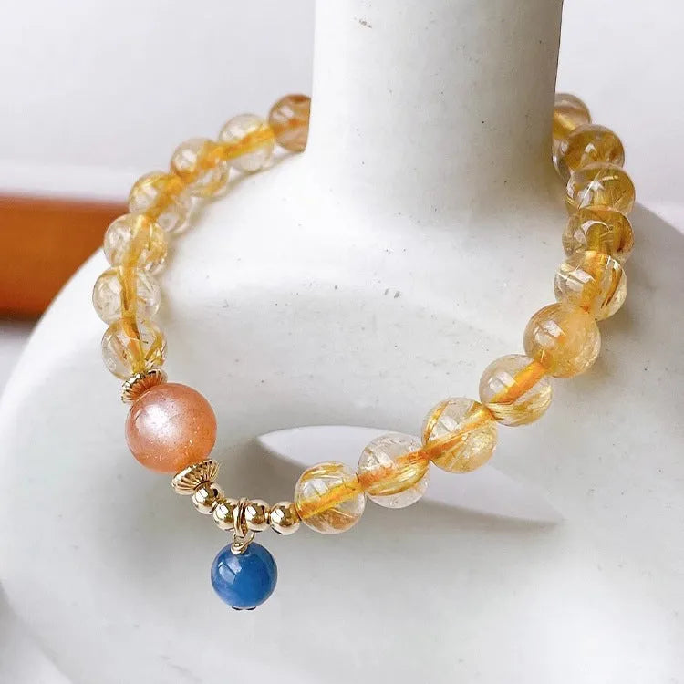 Gold rutilated quartz and sunstone bracelet with round diamond-shaped beads.