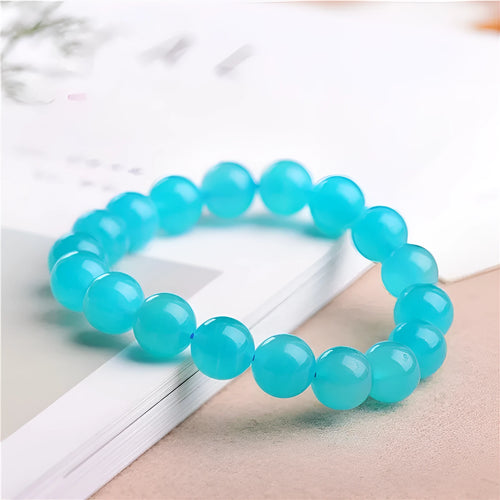 Natural blue-green Grade 7A Amazonite scattered beads in various sizes next to a finished crystal bracelet.