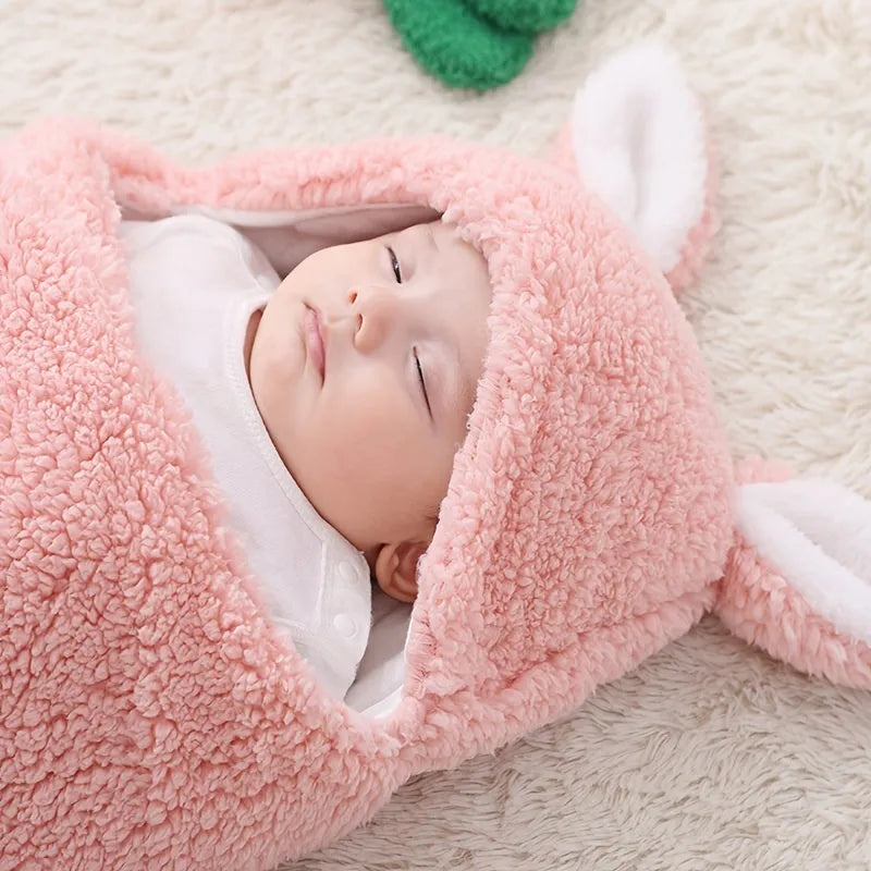 Baby wearing a blue adjustable cotton sleep sack with velcro swaddle closures and a head-protecting hood.