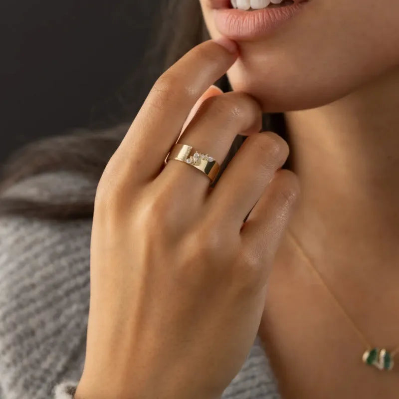 Gold electroplated copper ring for women with shining zircon details, shown on a finger.