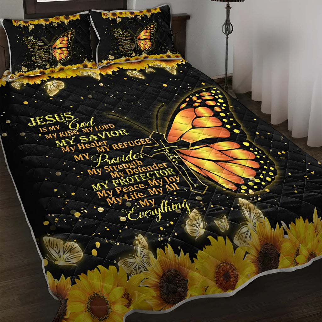 Three-piece black quilt set with butterfly and sunflower pattern, including quilt and two pillow shams, on a bed