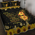 Three-piece black quilt set with butterfly and sunflower pattern, including quilt and two pillow shams, on a bed