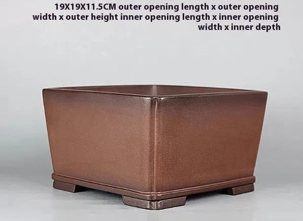 Handmade brown antique style purple clay flower pot on a windowsill.