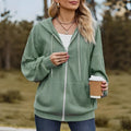 Green women's loose hooded zip-up coat on a hanger, showing front zipper and long sleeves.