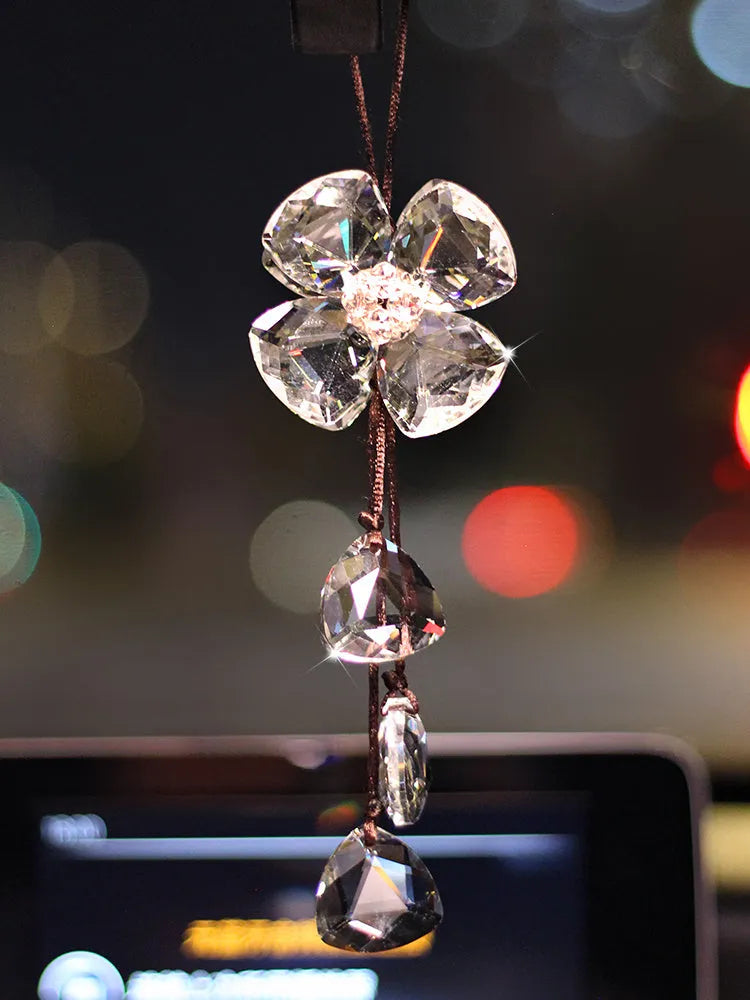 Crystal four leaf clover car pendant hanging, shown in one of four colour options: transparent, champagne, translucent black, or extremely shiny.