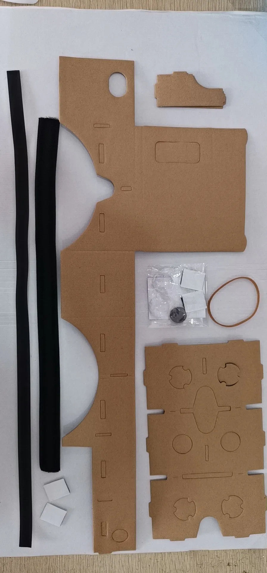 Pink and white flat-pack cardboard VR glasses viewer for smartphones with 3D lenses and straps.