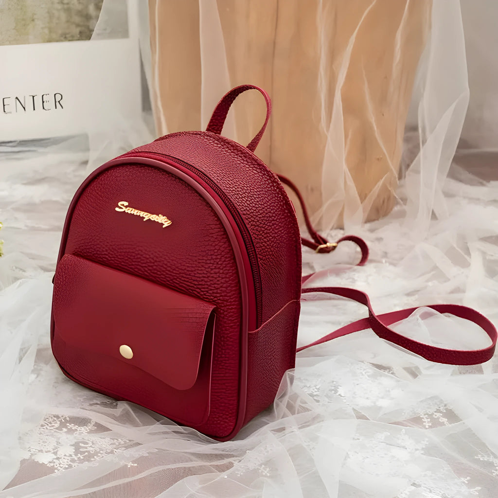 Small black PU women's backpack worn on shoulder, showing zip closure and compact size.