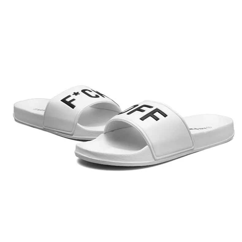 Men's black open-toe slippers with a textured rubber sole and soft viscose upper, shown on a wooden floor.
