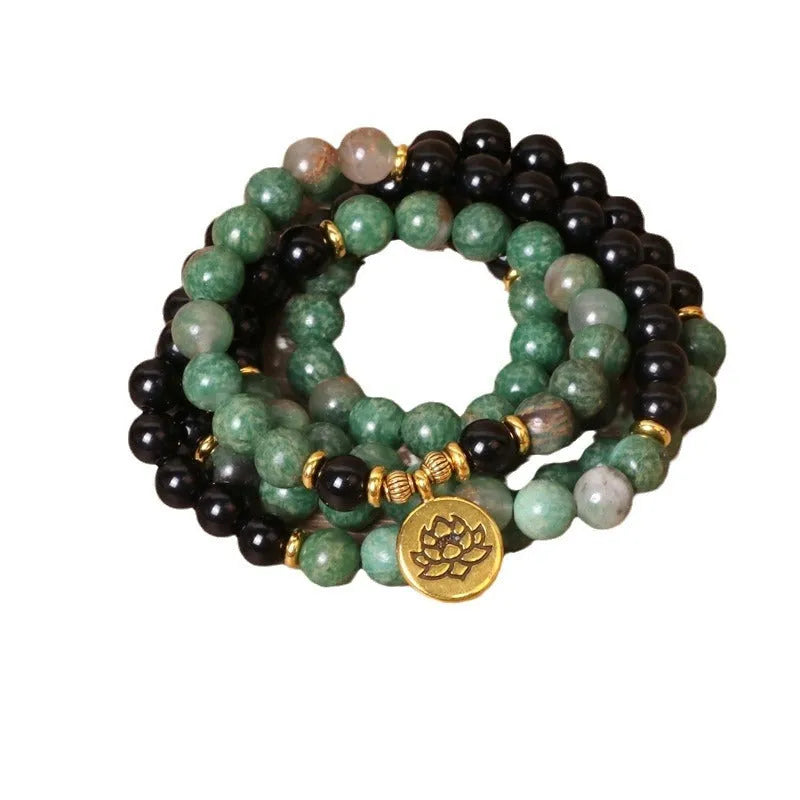 Green and black alloy bead long bracelet with elasticated band on a wrist.