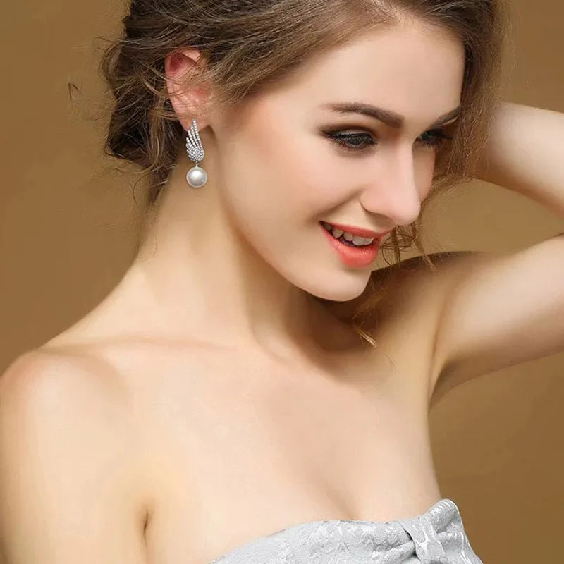 Sterling silver angel wing drop earrings with gold-plated stone inlay and diamond-cut texture.