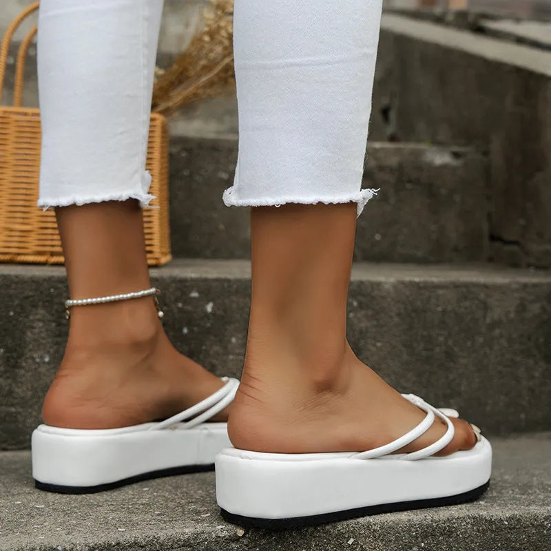 A pair of thick-soled, herringbone-pattern flip-flops on a sandy beach.