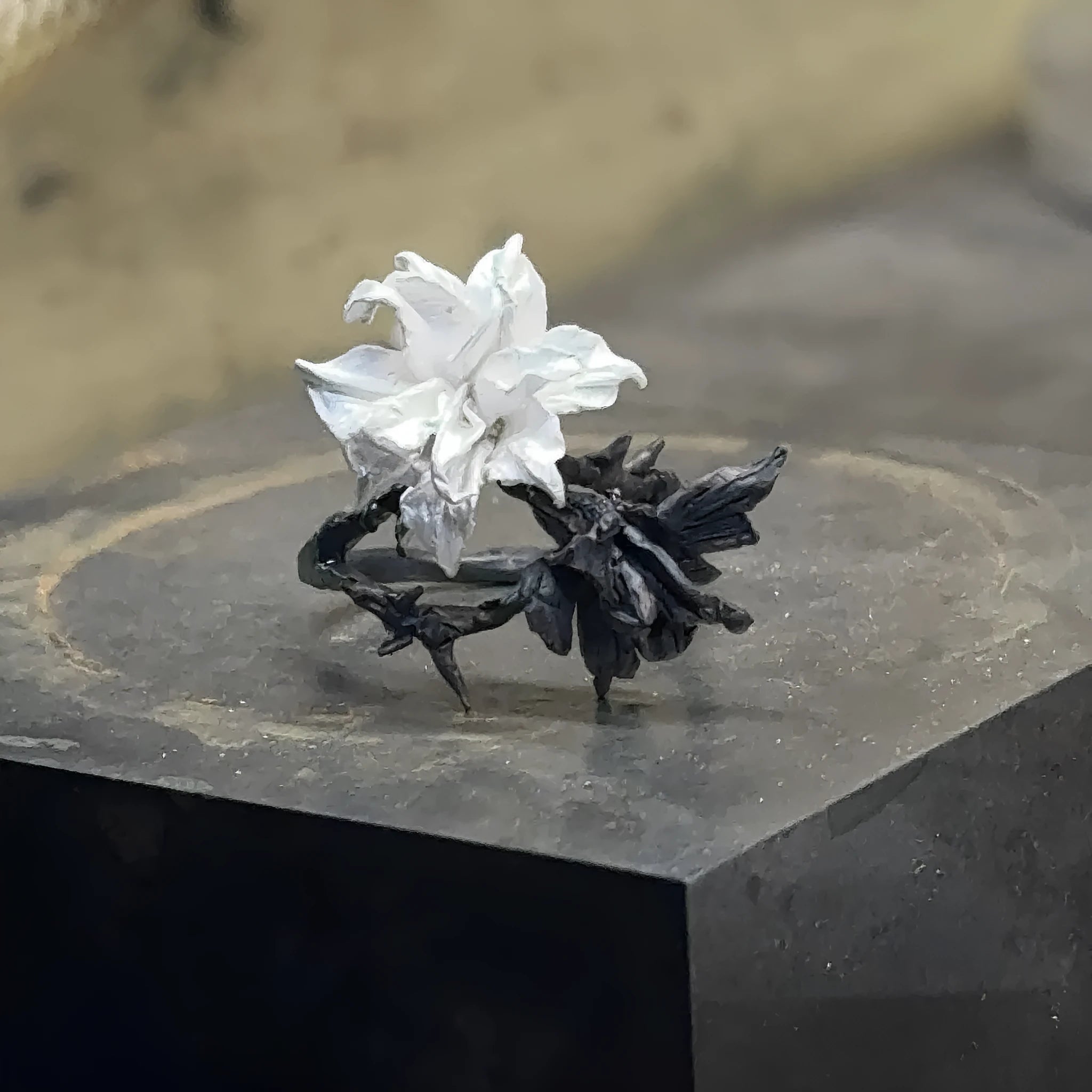 Open mouth copper ring with white and black colour separation and lily motif on a plain background