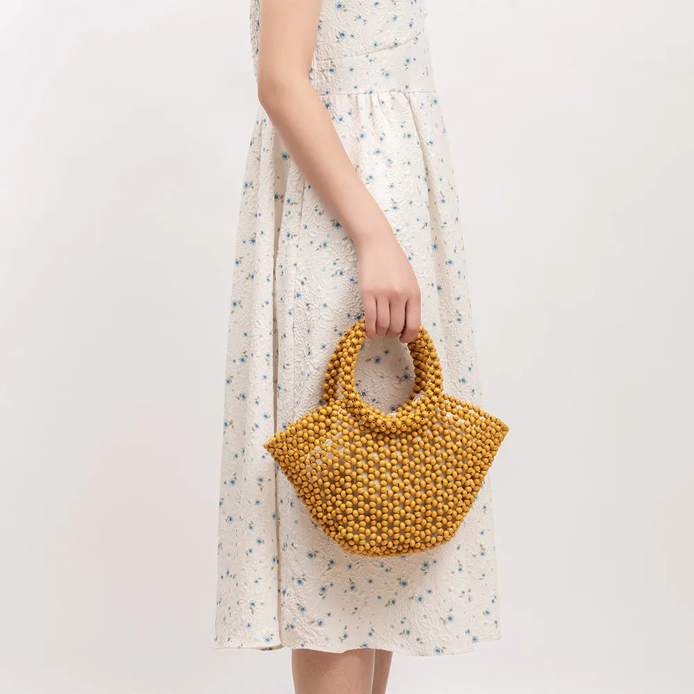 Hand-woven wooden bead beach bag in dumpling shape with strapless design.