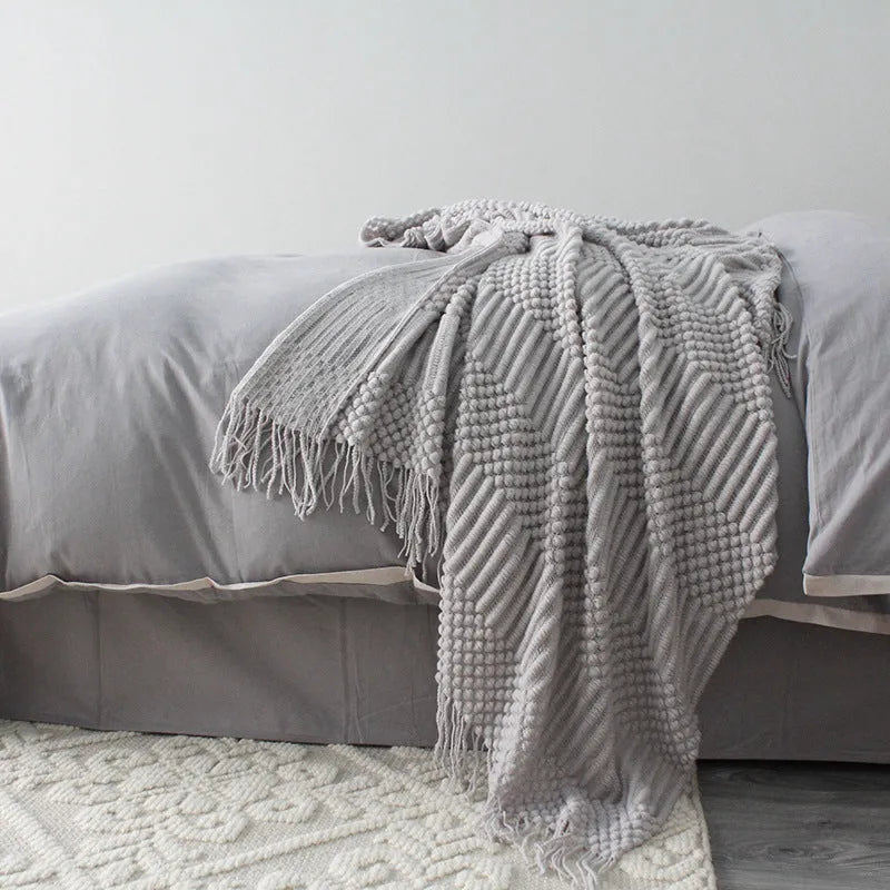 Small rectangular polyester nap blanket in dark grey, khaki, and light grey colours, measuring 127 by 170 cm.