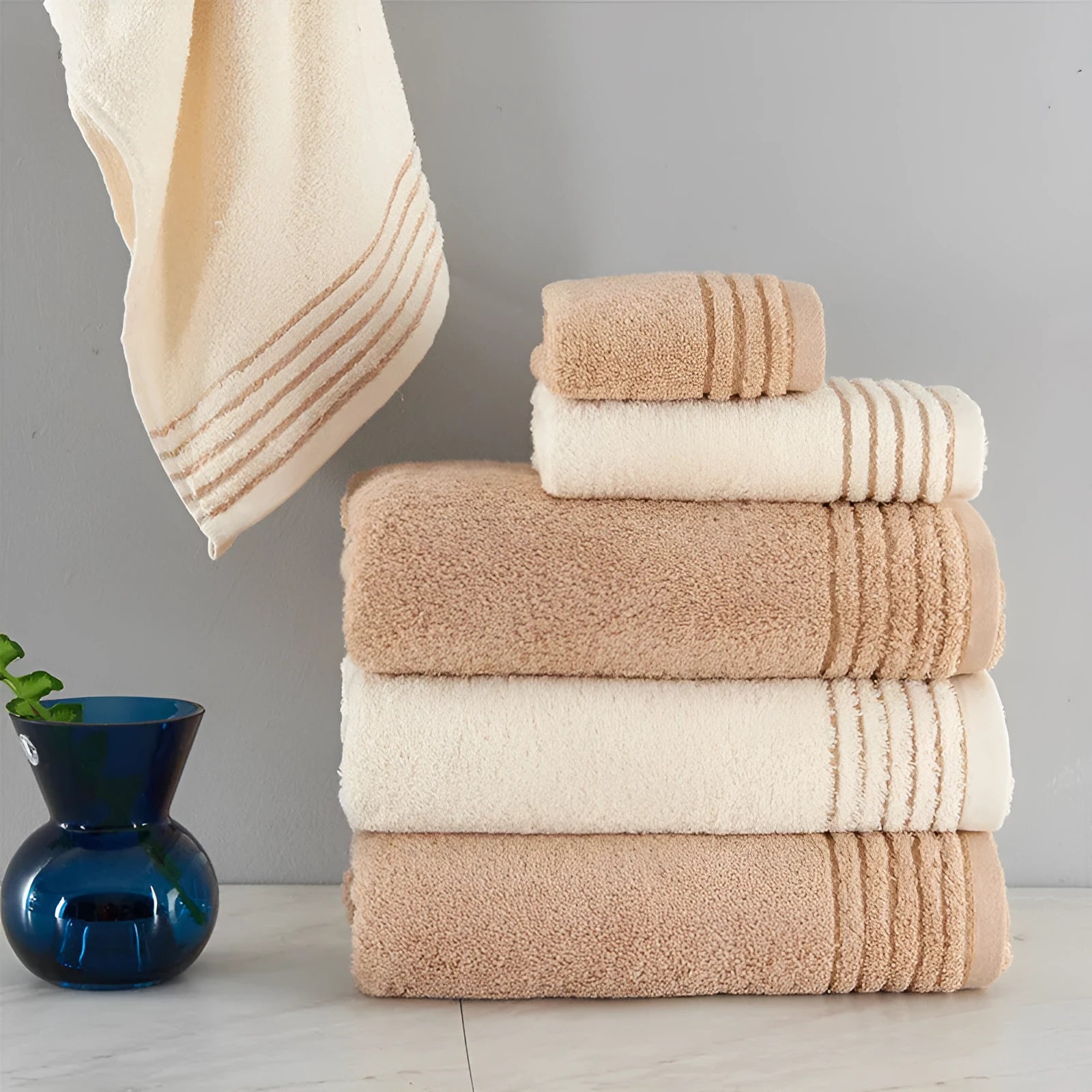 Cotton towel set in brown or beige showing bath sheet, hand towel, and face cloth sizes