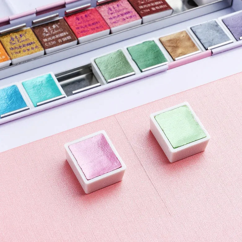 Set of pearlescent solid watercolour paint pans showing shimmering colours, available in 12 or 24 colour options.