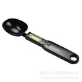 White digital spoon kitchen scale with LCD screen showing weight measurement.