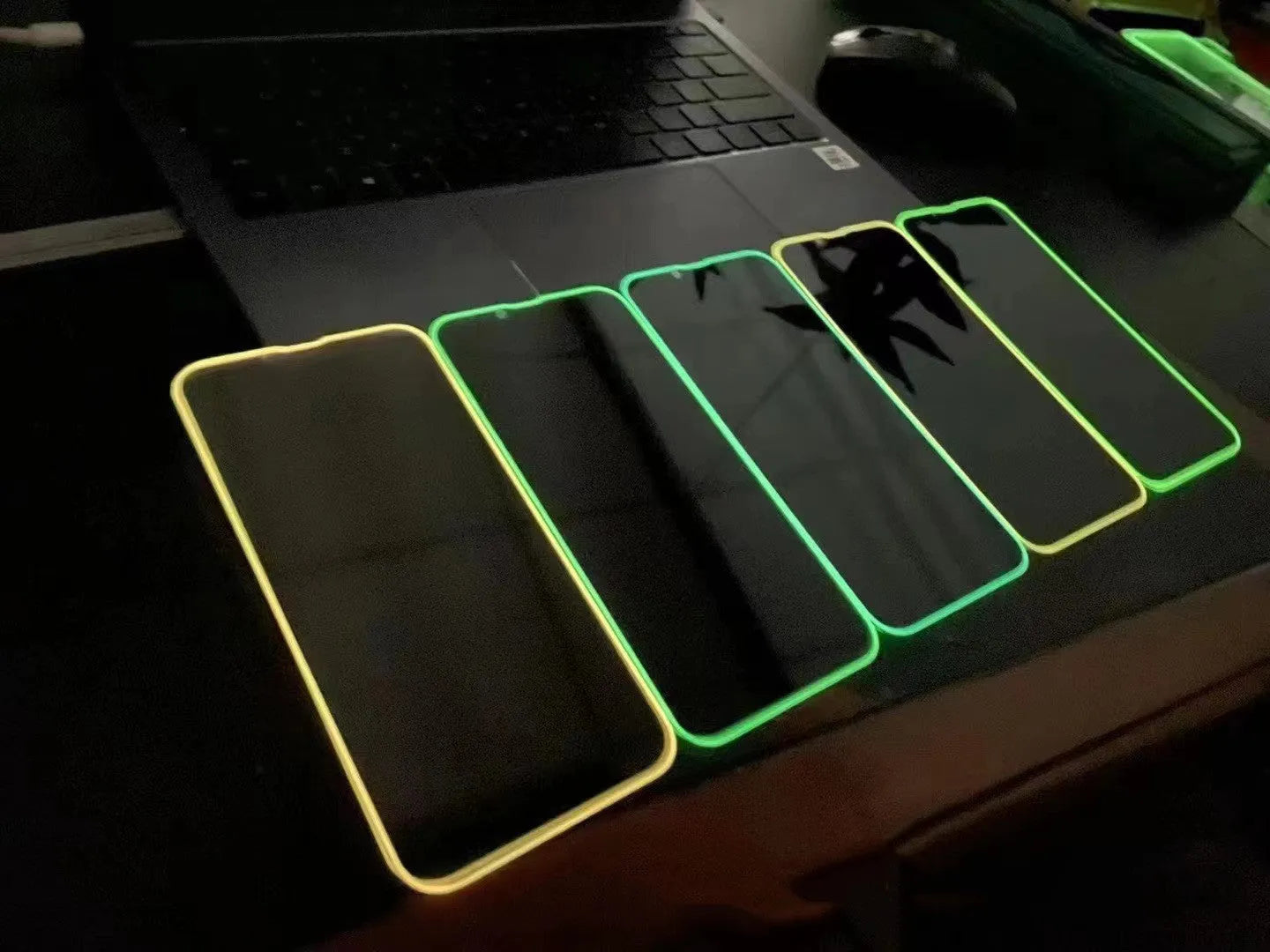 Fluorescent tempered glass screen protector for iPhone with glowing green edge on a phone