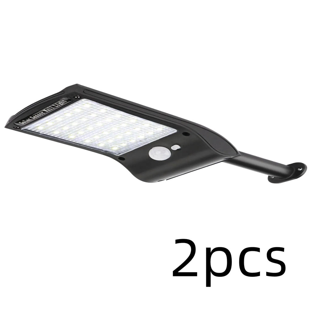 Black solar-powered LED wall light with motion sensor and diamond-patterned casing mounted on an exterior wall.