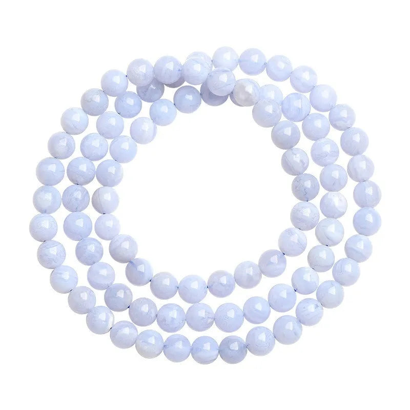 Blue agate bracelet with striped beads and a Ruyi charm on a wrist.