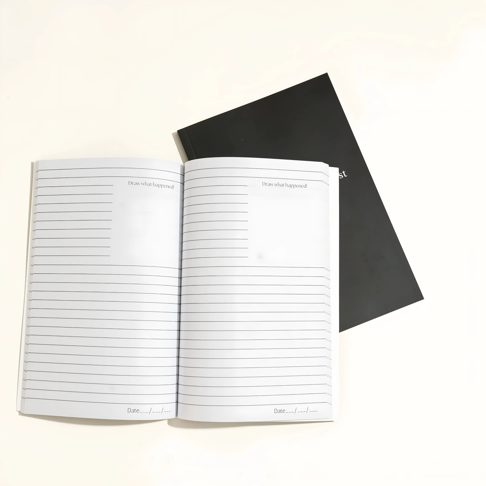 Black hardcover dream journal notebook with lined pages open.