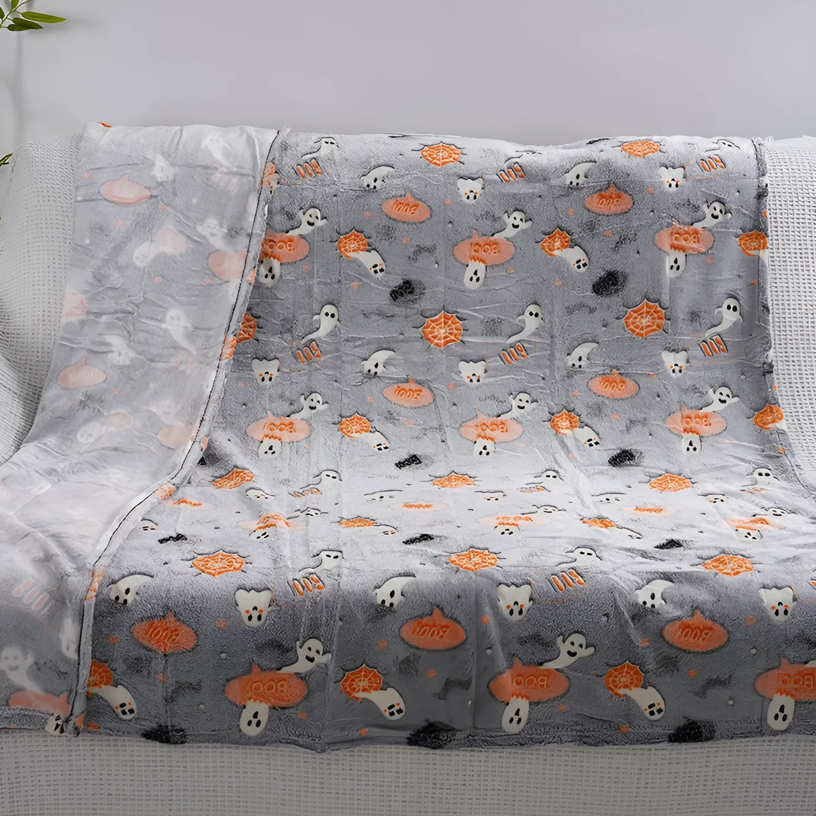 Colourful cartoon print flannel blanket shown draped over a sofa and next to an air conditioner unit.
