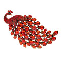 Colourful metal peacock brooch in red, green, and blue with rhinestone accents on a white background