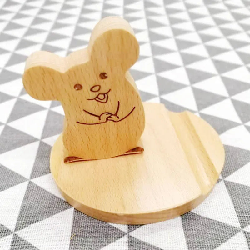 Sculpted beech wood lazy bracket phone holder with custom engraved text on a wooden desk.