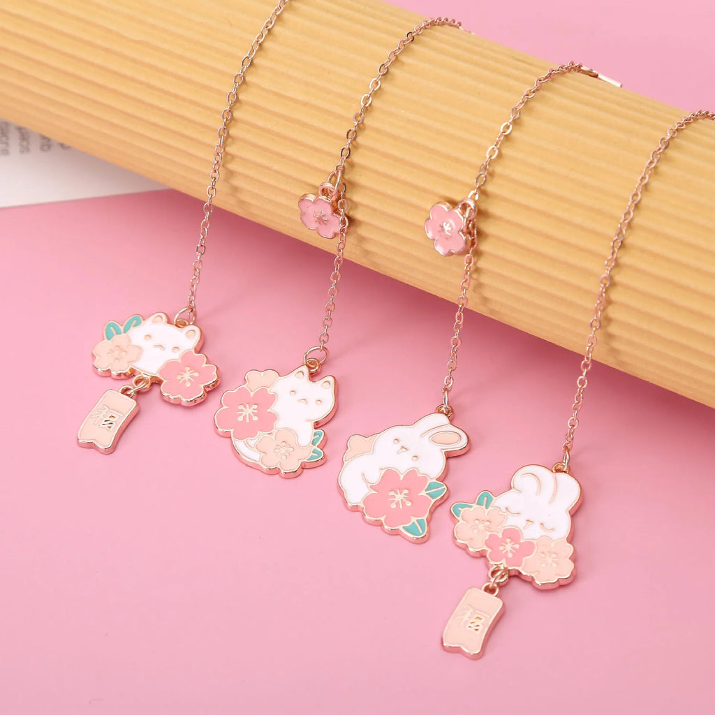Small metal bookmark pendant with cherry blossom and cartoon cat or rabbit design.