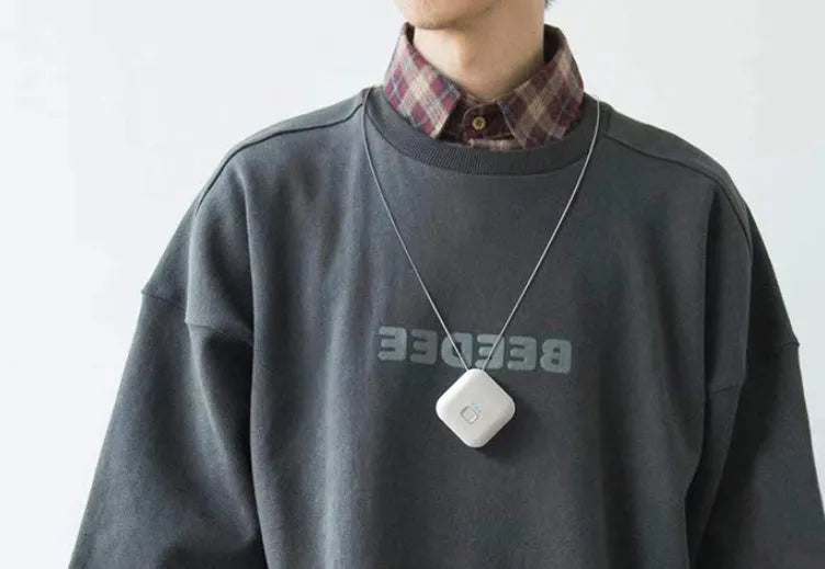 Mini USB portable air purifier necklace in pink, showing compact size and wearable design.