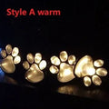 Black solar-powered animal paw print LED garden lights with four paw shapes connected to central solar pole