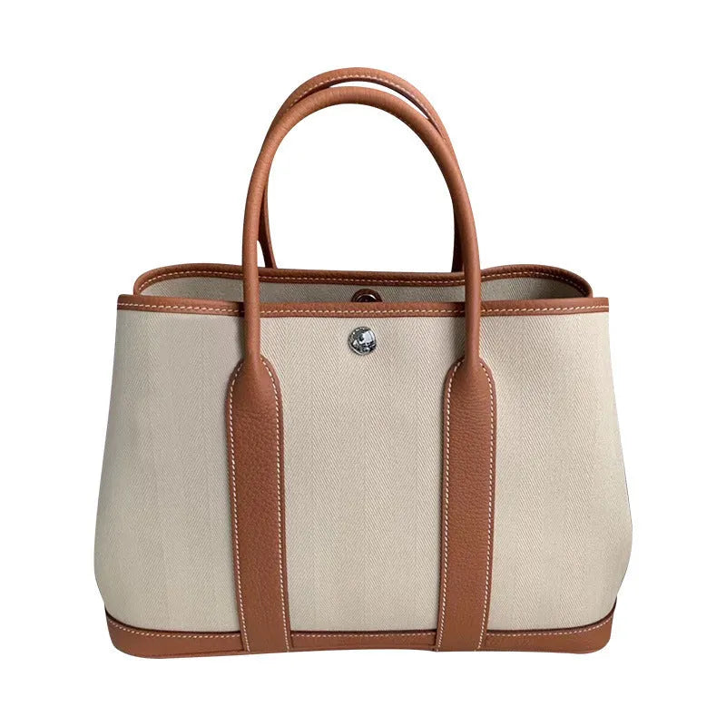 Women's canvas bucket tote bag with genuine leather trim showing internal zipper compartments and crossbody strap