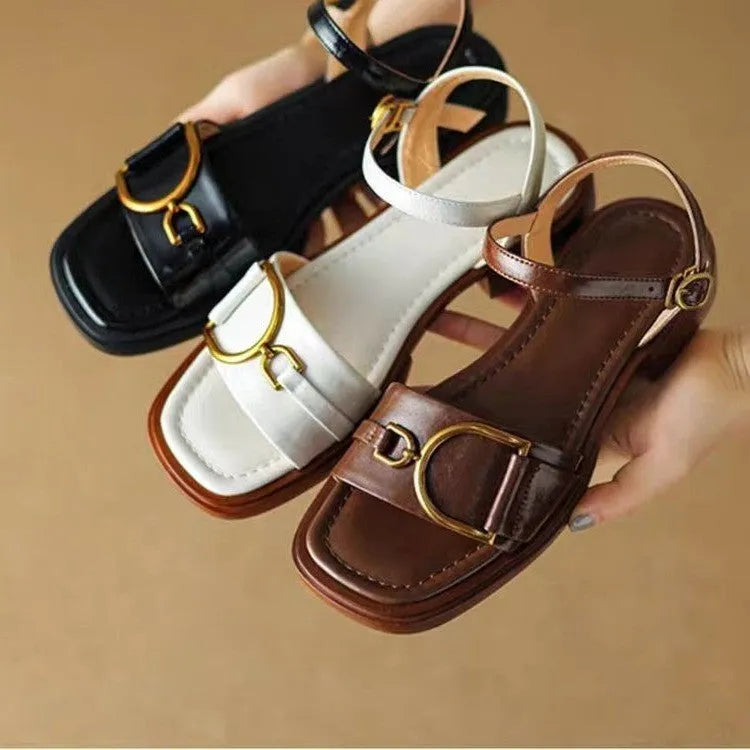 Women's black thick-soled leather sandals with a round toe and button fastening on a white background.