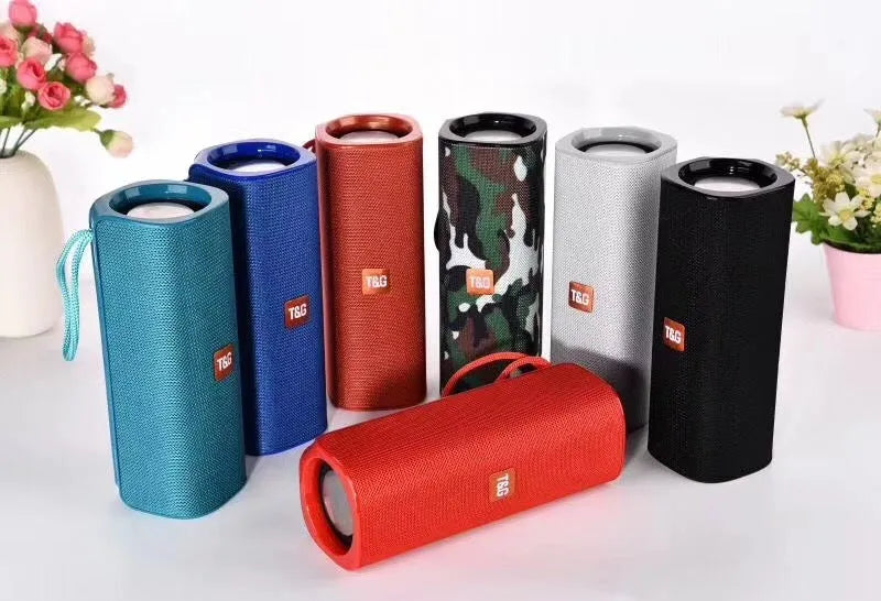 Cloth wireless Bluetooth speaker in multiple colours showing front grill and control buttons.