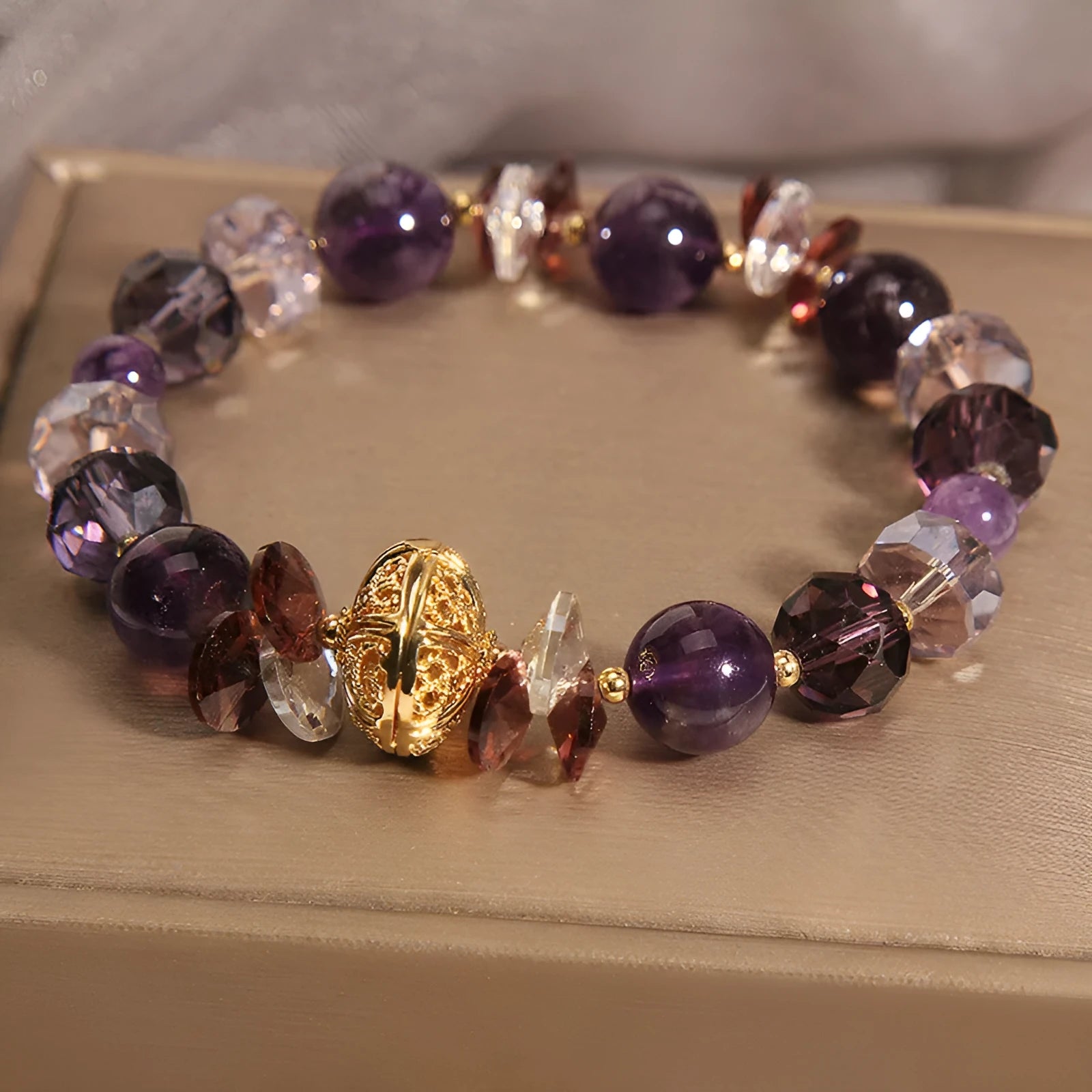 Purple crystal bracelet with pumpkin beads, wind chime charms, and rhinestone details on a wrist.