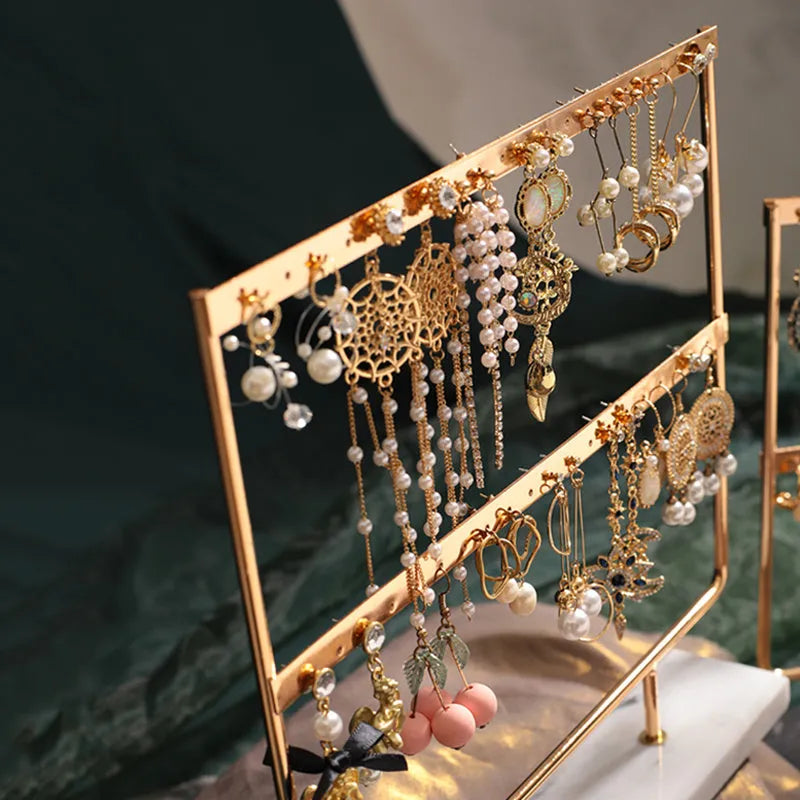 Alloy earring storage rack in green on a desktop holding multiple stud and hook earrings